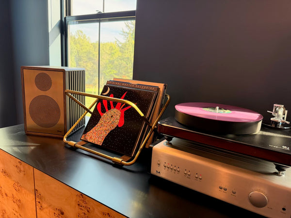 A turntable on an integrated amplifier, beside a Sieg S14 speaker and a record rack